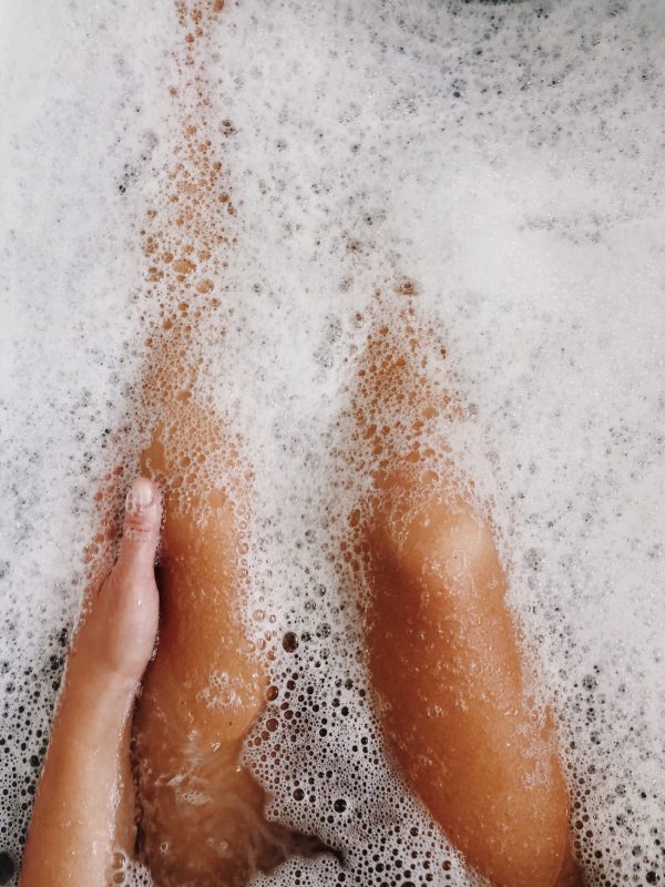 Tanned legs personal perspective in the bubble bath